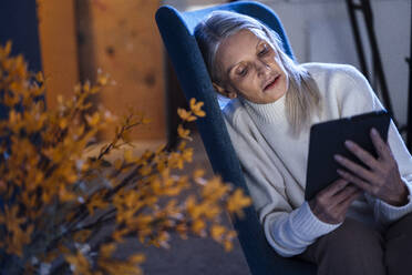 Senior woman using tablet PC resting on chair - JOSEF08614