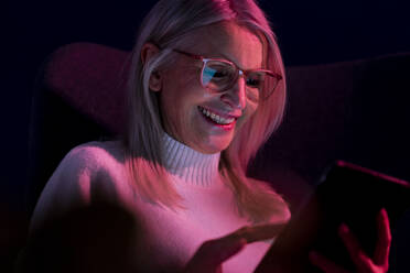 Lächelnde ältere Frau mit Tablet-PC in der Dunkelkammer - JOSEF08659