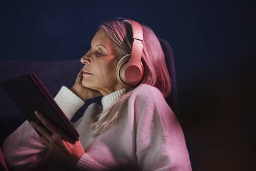 Ältere Frau hält Tablet-PC und hört Musik über Kopfhörer - JOSEF08669