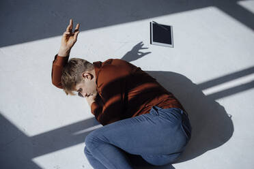 Businessman gesturing lying down on floor in office - JOSEF08701