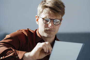 Businessman wearing eyeglasses working on tablet PC at office - JOSEF08723