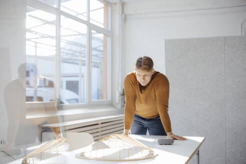Architekt, der ein blattförmiges Modell betrachtet, das auf einem Schreibtisch im Büro liegt - JOSEF08751