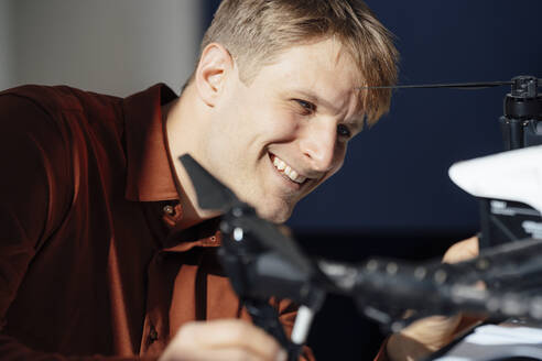 Lächelnder Ingenieur, der eine Drohne im Büro analysiert - JOSEF08822