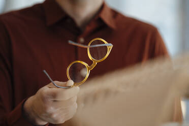 Hand of businessman holding eyeglasses in office - JOSEF08833