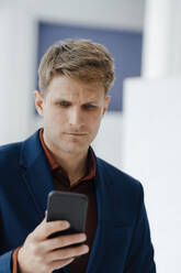 Businessman using mobile phone in office - JOSEF08843