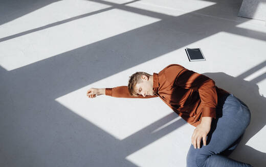 Geschäftsmann ruht sich mit einem Tablet-PC auf dem Boden im Büro aus - JOSEF08857