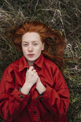 Junge Frau mit rotem Kopf auf einer Wiese liegend - OGF01220