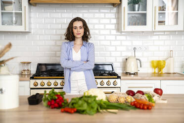 Confident woman with arms crossed in kitchen at home - VPIF05845