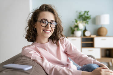 Happy woman wearing eyeglasses in living room at home - VPIF05914