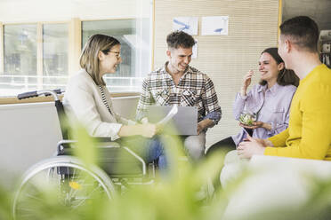 Young business people having a meeting in office with woman sitting in wheelchair - UUF25706