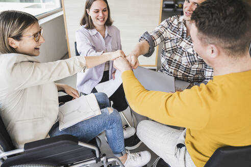 Business team touching fists in office - UUF25714