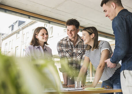 Smiling young business people having a meeting in office - UUF25736