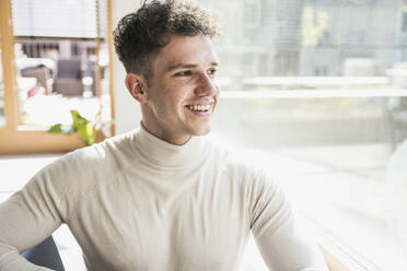 Smiling young businessman looking out of window - UUF25753