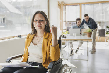 Portrait of young businesswoman in wheelchair in office - UUF25763