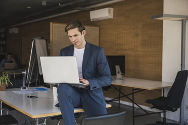 Businessman using laptop in office - UUF25776