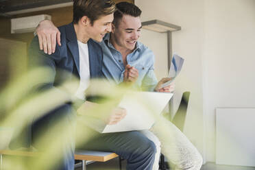 Two happy colleagues with laptop and documents in office - UUF25783