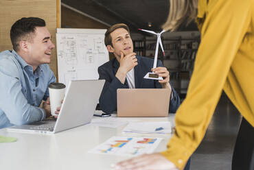 Geschäftsteam mit Windradmodell bei einer Besprechung im Büro - UUF25810