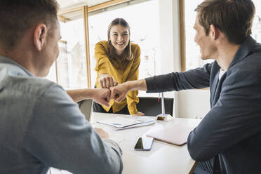 Happy business team touching fists in office - UUF25815