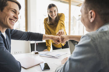 Happy business team touching fists in office - UUF25816