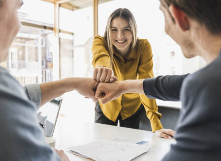 Happy business team touching fists in office - UUF25817
