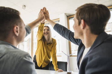 Happy business team high fiving in office - UUF25820