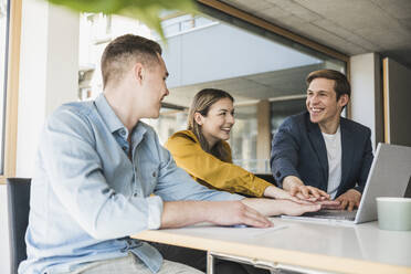 Happy business team stacking hands in office - UUF25825