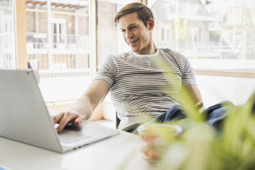 Businessman using laptop at desk in office - UUF25837