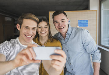 Glückliche Geschäftsleute machen ein Selfie im Büro - UUF25845