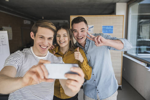 Happy business people taking a selfie in office - UUF25846