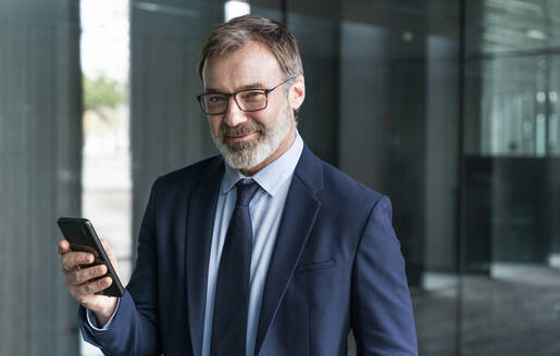 Smiling businessman holding smart phone - OIPF01556