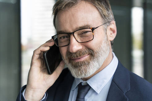 Älterer lächelnder Geschäftsmann, der mit einem Mobiltelefon spricht - OIPF01558