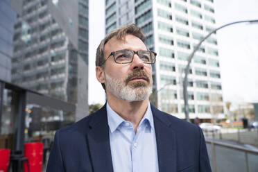 Businessman with eyeglasses contemplating near building - OIPF01584