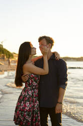 Young woman embracing boyfriend at beach of sea on sunny day - SSGF00739