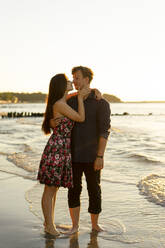 Young couple rubbing noses standing at beach on sunny day - SSGF00740