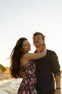 Glückliches junges Paar steht am Strand an einem sonnigen Tag - SSGF00742