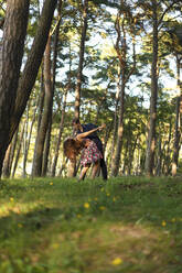 Young couple dancing by trees in forest - SSGF00747