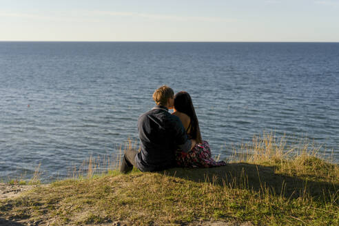 Pärchen vor dem Meer sitzend an einem sonnigen Tag - SSGF00754