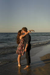 Junges zärtliches Paar küsst sich am Strand bei Sonnenuntergang - SSGF00761