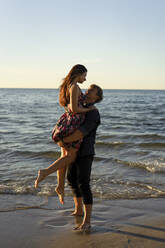 Boyfriend lifting girlfriend at beach on sunny day - SSGF00763