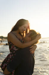 Young couple embracing each other at beach on sunny day - SSGF00764