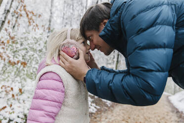 Vater und Tochter berühren ihre Nasen im Winterwald - TYF00136