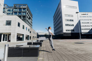 Junge Geschäftsfrau springt auf Gehweg im Finanzviertel - MEUF05159