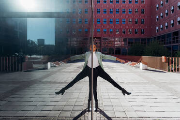 Spiegelung einer auf einem Bein balancierenden Geschäftsfrau im Stadtzentrum - MEUF05185