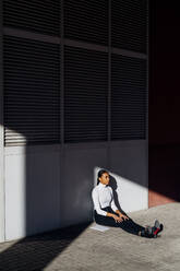 Young businesswoman sitting on footpath - MEUF05190