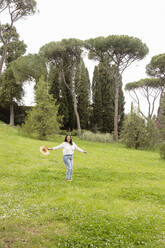 Frau mit Hut genießt auf grünem Gras im Park - EIF03956