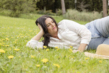 Smiling woman lying on grass at park - EIF03959