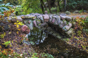 Poland, Masovian Voivodeship, Warsaw, Small stone arch bridge in Skaryszew Park - ABOF00777