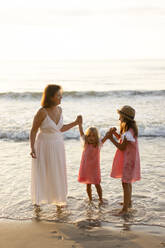 Happy mother and daughters having fun at beach - SSGF00804