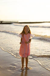 Happy girl standing in front of sea at beach - SSGF00812