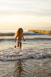 Cute girl wearing underwear playing in water on beach stock photo